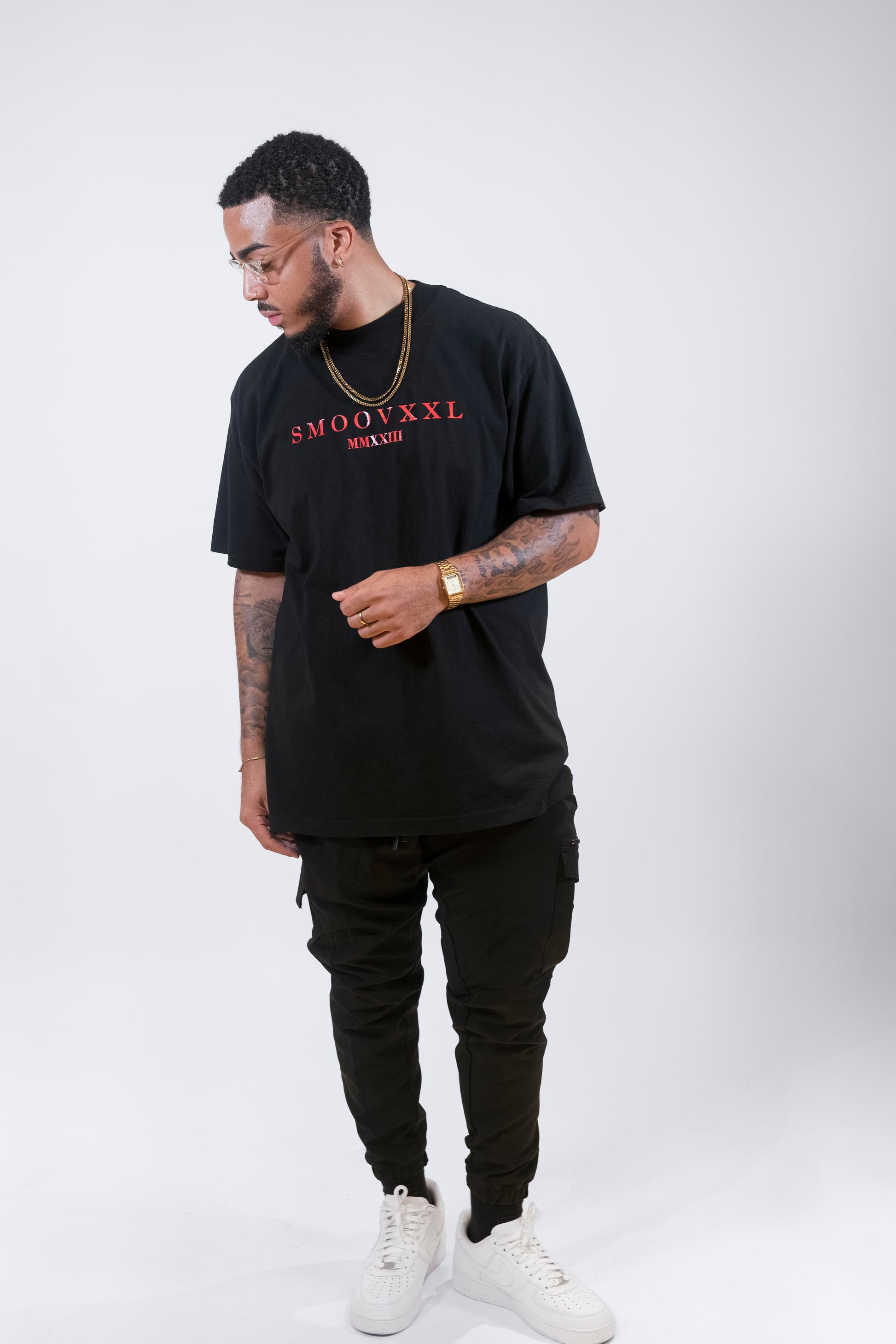 Man wearing a black tee with a design that shows the SMOOVXXL logo in red